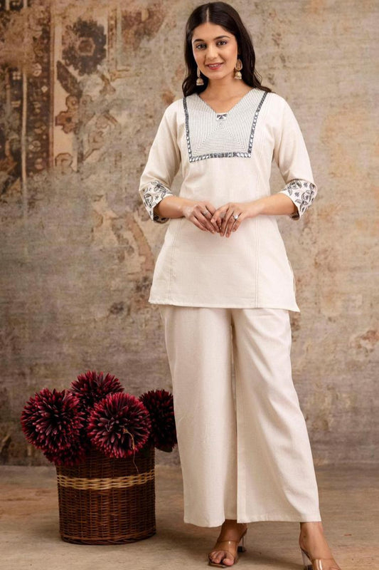 Woman wearing a traditional outfit with a textured wall and basket of flowers in the background